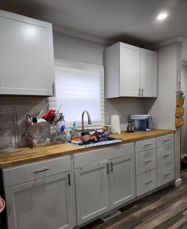 kitchen with crown molding, white cabinetry, butcher block counters, and sink