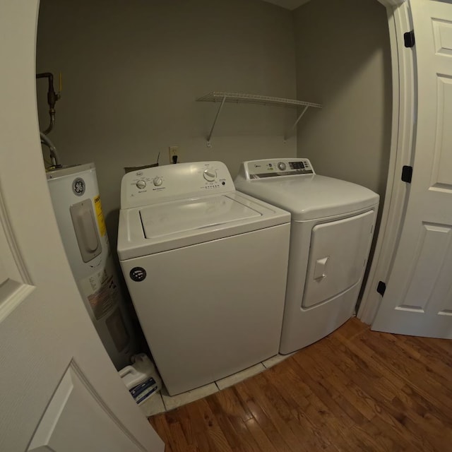 clothes washing area with wood-type flooring, electric water heater, and washing machine and clothes dryer