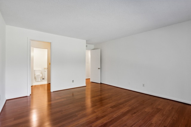 spare room featuring a textured ceiling and dark hardwood / wood-style flooring