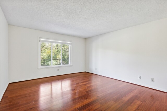 empty room with a textured ceiling and dark wood-type flooring