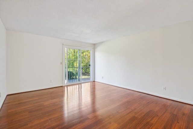 spare room featuring dark hardwood / wood-style flooring and a textured ceiling