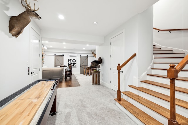 recreation room featuring a barn door, carpet floors, and a wall mounted AC