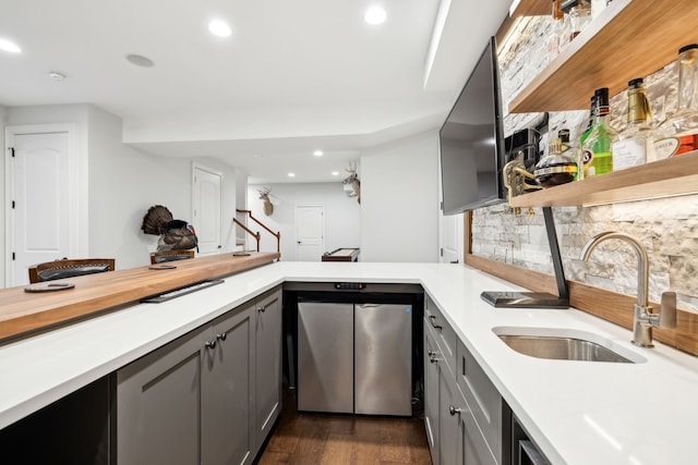 kitchen featuring sink, dark wood-type flooring, gray cabinets, and kitchen peninsula