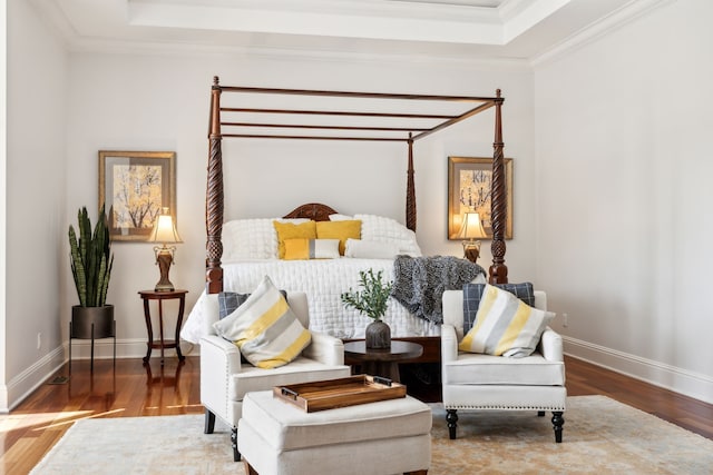 bedroom featuring a raised ceiling, wood-type flooring, and crown molding