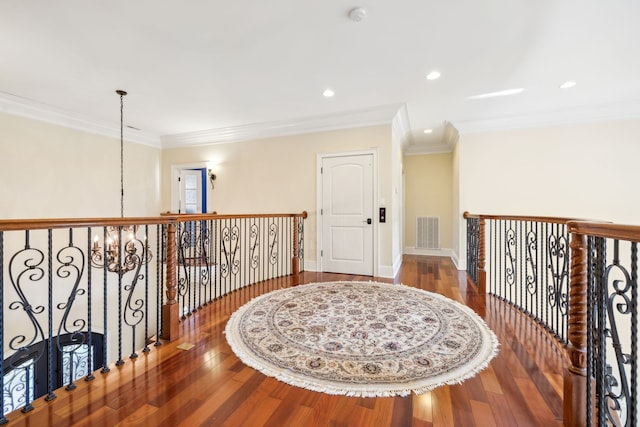 hall with hardwood / wood-style flooring, ornamental molding, and a chandelier