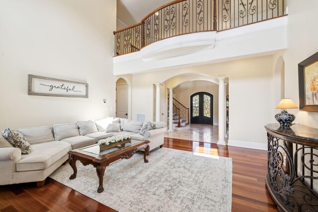 2971 Spanntown Rd, Arrington, TN 37014 - living room featuring arched walkways, ornate columns, a high ceiling, wood finished floors, and baseboards