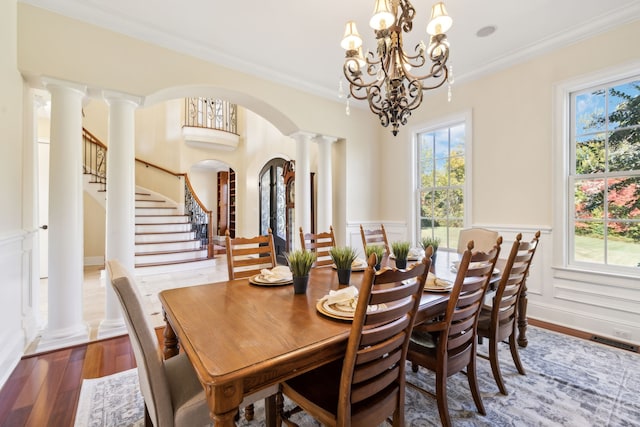 dining area with ornamental molding, decorative columns, hardwood / wood-style floors, and a wealth of natural light