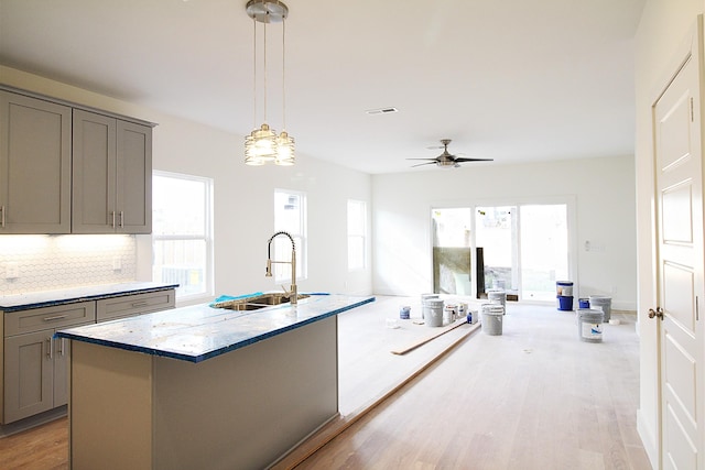 kitchen with gray cabinetry, decorative backsplash, sink, and light hardwood / wood-style flooring