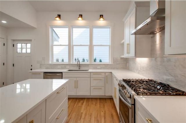 kitchen featuring wall chimney range hood, white cabinets, stainless steel appliances, and light hardwood / wood-style floors