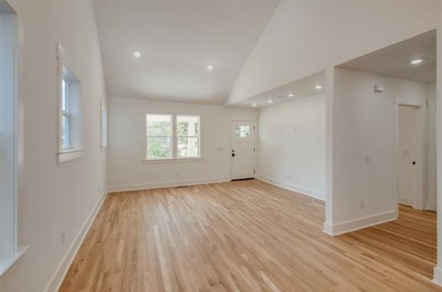 empty room with high vaulted ceiling and light wood-type flooring