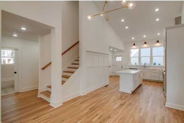 kitchen featuring a healthy amount of sunlight, a center island, high vaulted ceiling, and white cabinetry