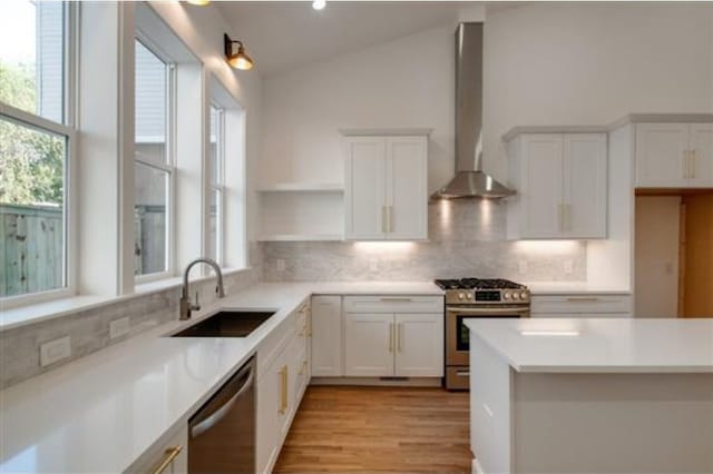 kitchen featuring wall chimney exhaust hood, white cabinetry, stainless steel appliances, and lofted ceiling