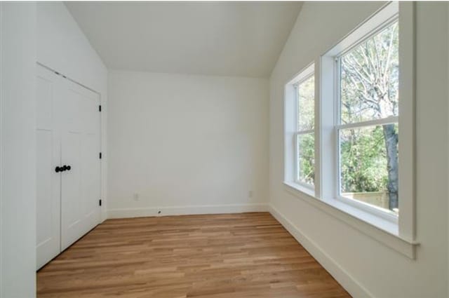 empty room with lofted ceiling and light hardwood / wood-style flooring