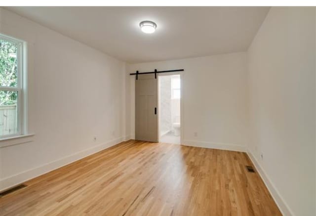 empty room with a barn door and light hardwood / wood-style flooring