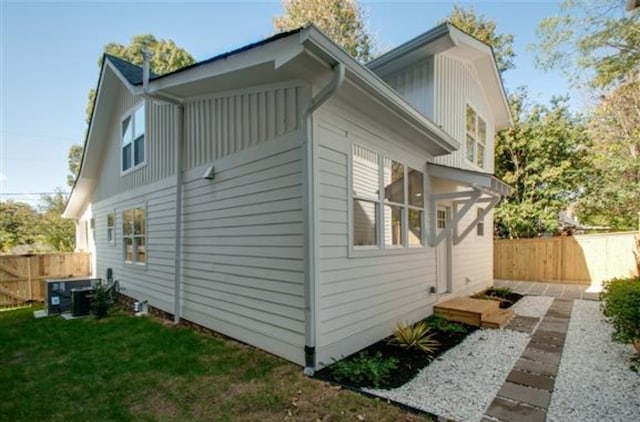 view of side of home with a yard and central AC