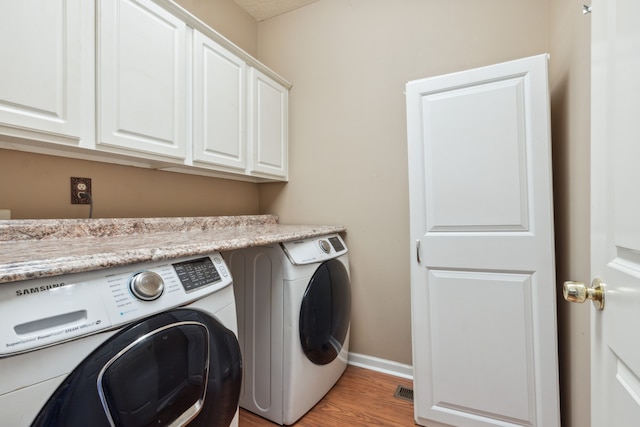 laundry area featuring light hardwood / wood-style flooring, washing machine and dryer, and cabinets