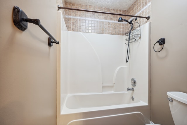 bathroom featuring toilet, tiled shower / bath combo, and a textured ceiling