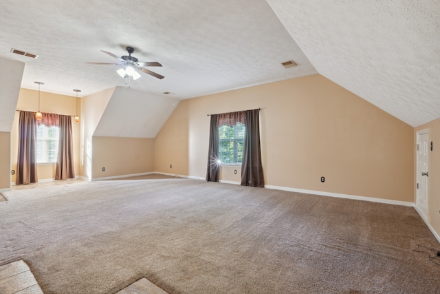 additional living space featuring a wealth of natural light, lofted ceiling, a textured ceiling, and ceiling fan