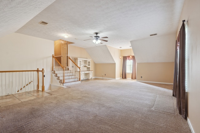 additional living space with light carpet, a textured ceiling, vaulted ceiling, and ceiling fan