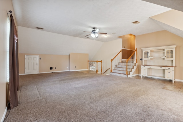 unfurnished living room with carpet, a textured ceiling, vaulted ceiling, and ceiling fan