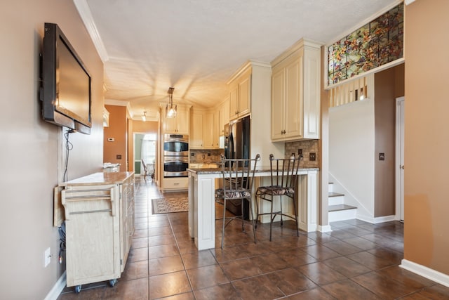 kitchen featuring tasteful backsplash, cream cabinets, a kitchen bar, pendant lighting, and stainless steel double oven