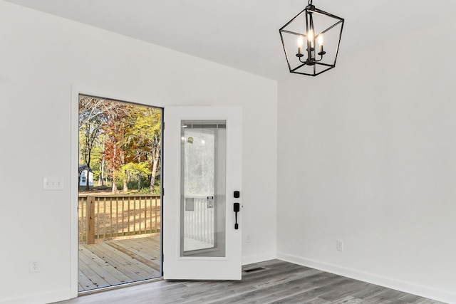 doorway to outside with an inviting chandelier and wood-type flooring