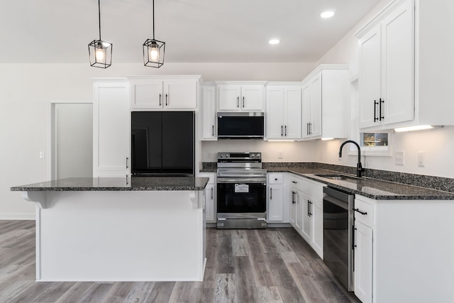 kitchen with stainless steel appliances, sink, hardwood / wood-style floors, pendant lighting, and white cabinets