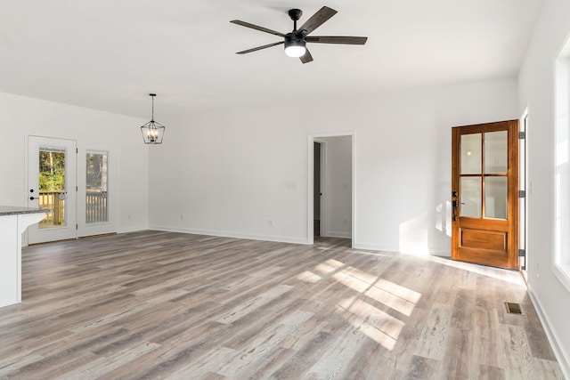 unfurnished living room with light hardwood / wood-style floors and ceiling fan with notable chandelier