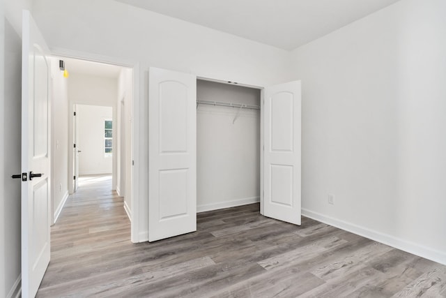 unfurnished bedroom with a closet and light hardwood / wood-style floors