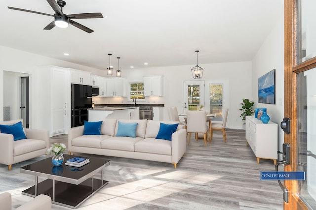 living room featuring sink, light hardwood / wood-style flooring, and ceiling fan