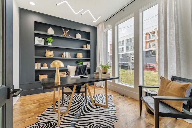 office area with light hardwood / wood-style flooring and built in shelves