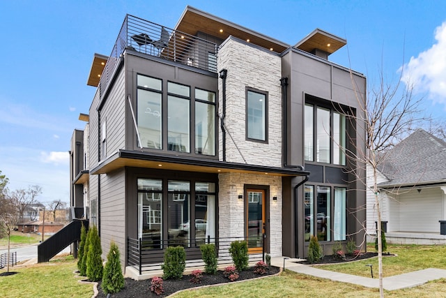 contemporary home with a balcony and a front lawn