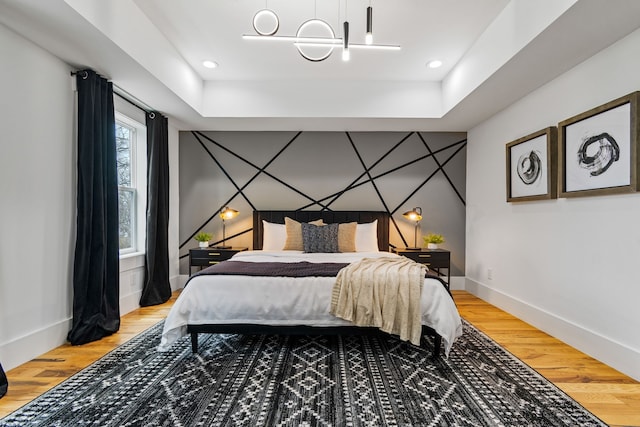 bedroom featuring hardwood / wood-style flooring and a raised ceiling