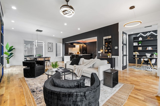 living room with a notable chandelier, built in features, and light wood-type flooring