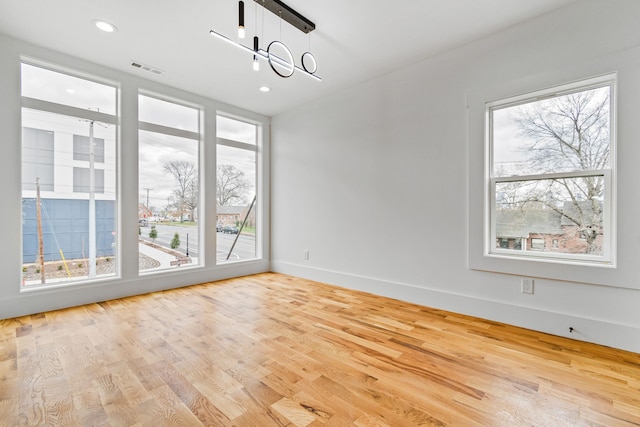 unfurnished dining area featuring light hardwood / wood-style flooring, a healthy amount of sunlight, and a chandelier