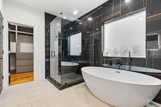 bathroom featuring plus walk in shower and tile walls