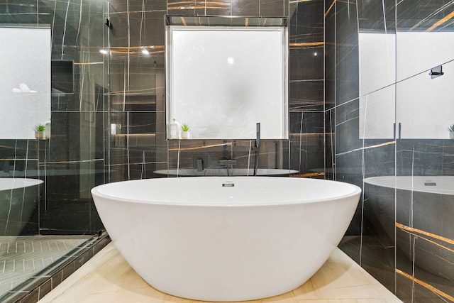 bathroom with plus walk in shower, tile patterned floors, and tile walls