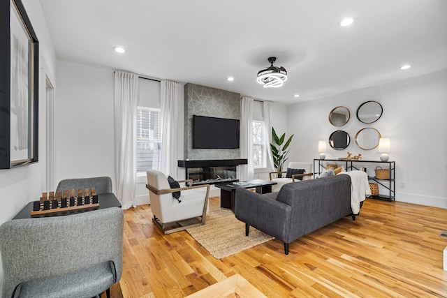 living room featuring a large fireplace, a healthy amount of sunlight, and light wood-type flooring