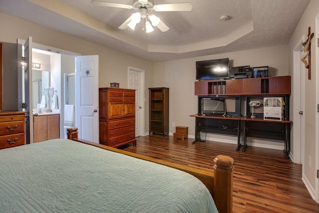 bedroom with dark wood-type flooring, a tray ceiling, a textured ceiling, and ceiling fan