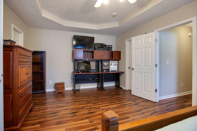 office area featuring a textured ceiling, dark wood-type flooring, and a raised ceiling