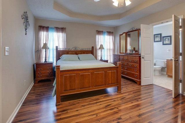 bedroom with ceiling fan, multiple windows, a tray ceiling, and dark hardwood / wood-style flooring