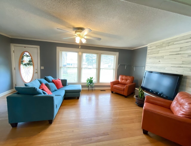 living room with light wood-type flooring, a textured ceiling, ceiling fan, and ornamental molding