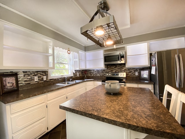 kitchen featuring white cabinets, a kitchen island, appliances with stainless steel finishes, and tasteful backsplash