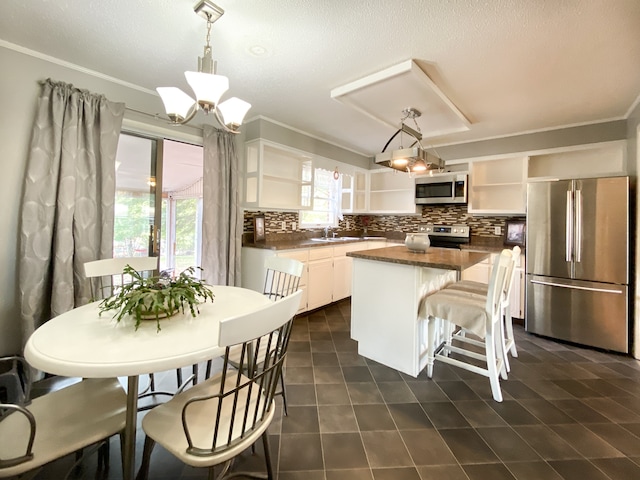 kitchen featuring stainless steel appliances, hanging light fixtures, white cabinets, and a center island