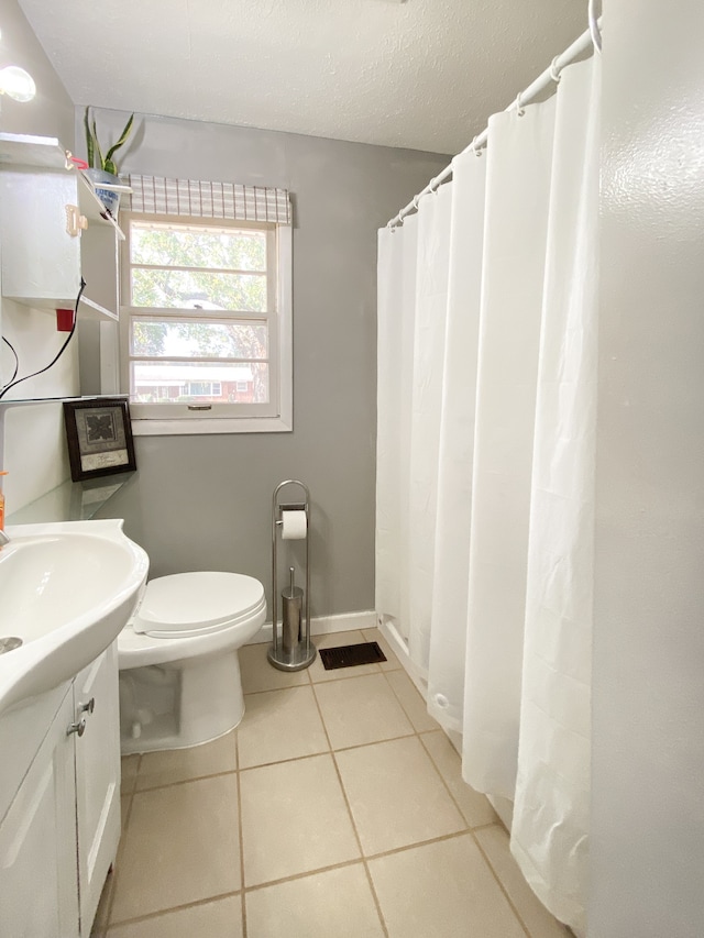 bathroom featuring toilet, vanity, a textured ceiling, and tile patterned flooring