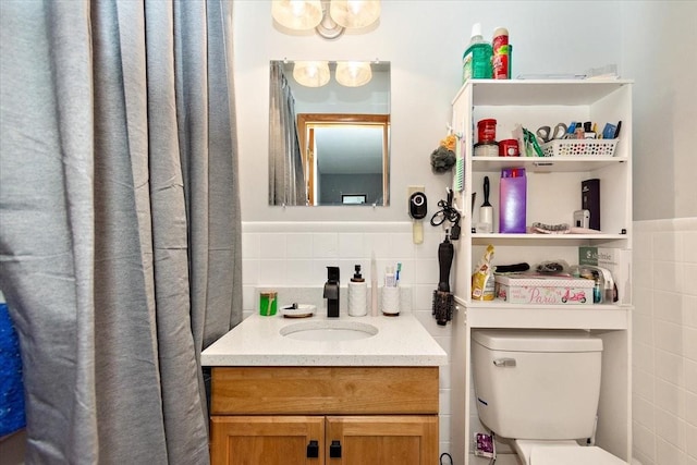 bathroom with vanity, toilet, and tile walls