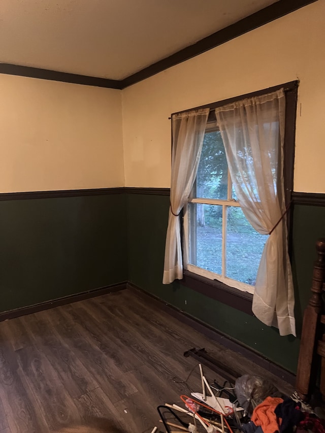 unfurnished room with ornamental molding and dark wood-type flooring