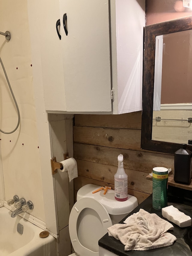 bathroom featuring wooden walls, washtub / shower combination, and toilet