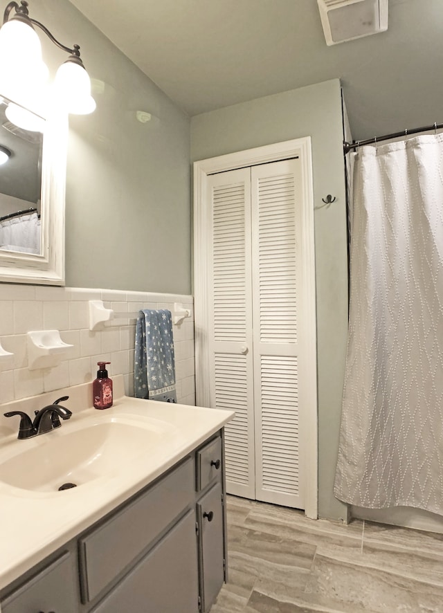 bathroom featuring vanity, hardwood / wood-style floors, and tile walls