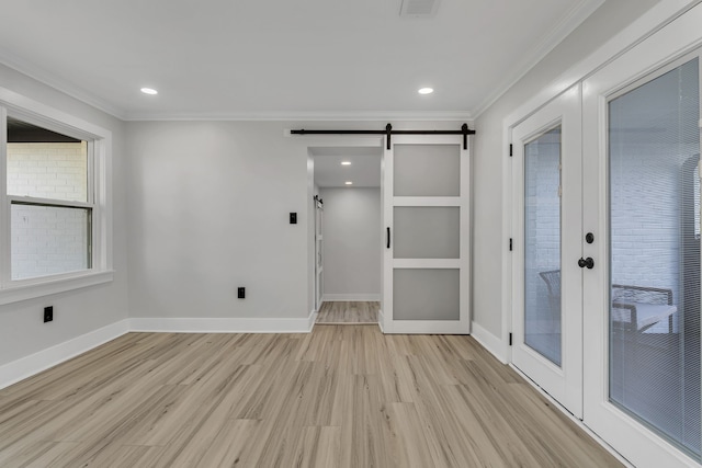 empty room with crown molding, a barn door, light hardwood / wood-style flooring, and french doors